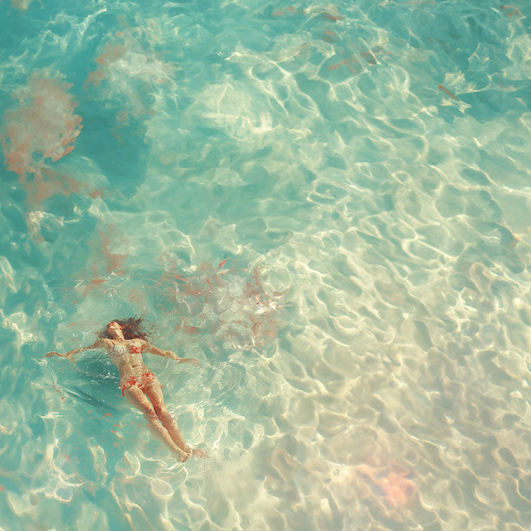 Mujer flotando en aguas cristalinas y turquesas, vista aérea