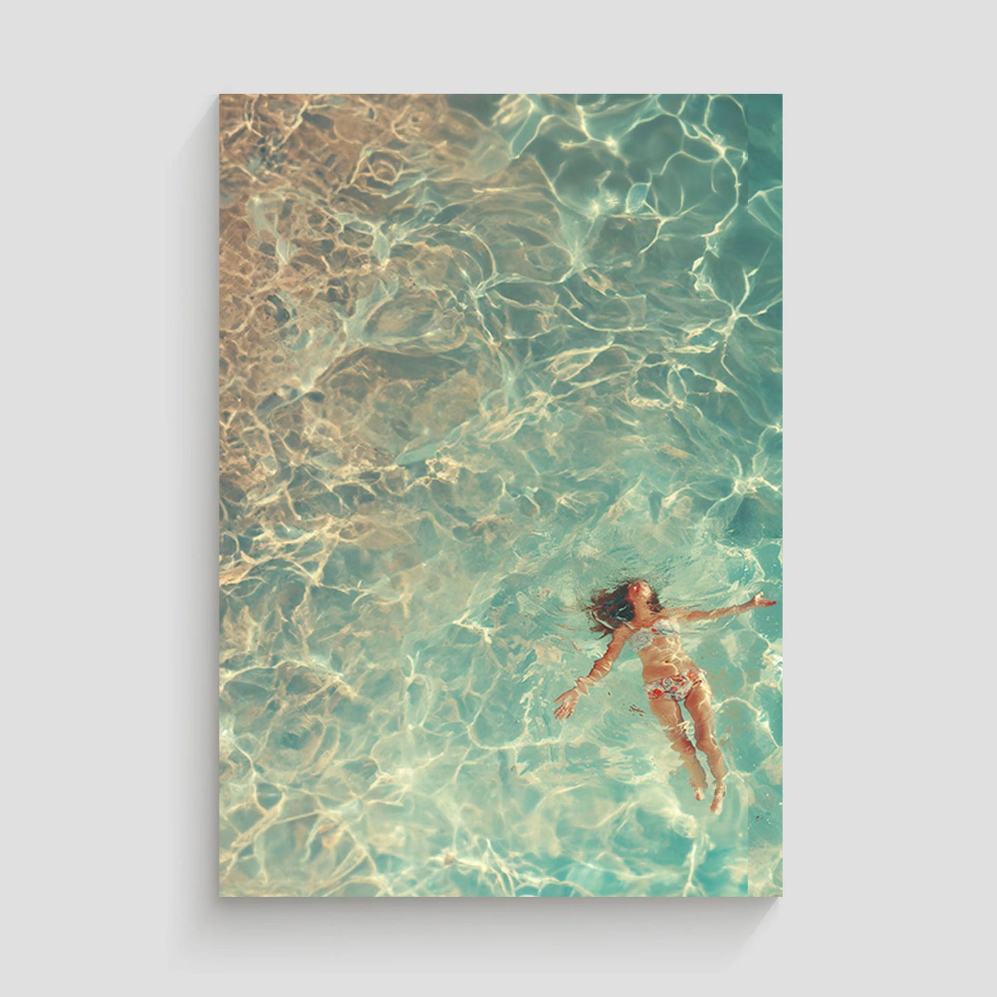 Mujer flotando en aguas cristalinas y turquesas, vista aérea.